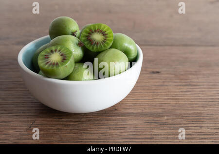 Hardy kiwi o kiwi berry nel recipiente di ceramica sul tavolo Foto Stock