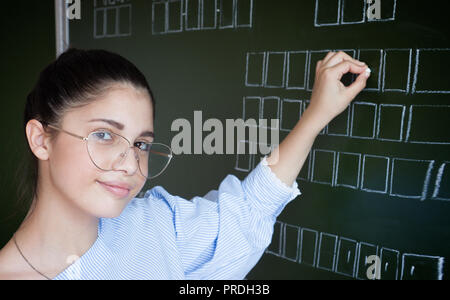 Studente che scrive sulla lavagna con gesso in aula Foto Stock