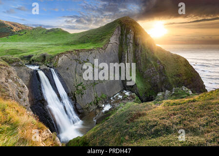 Speke's Mill bocca una cascata che scorre su un suggestivo anomalia geologica lungo la North Devon costa al tramonto. Foto Stock