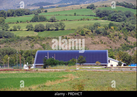 Il tetto a energia solare di una grande superficie curva su un edificio comunale di un piccolo villaggio dei Pirenei Foto Stock