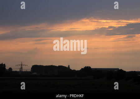 Tralicci di elettricità nel tramonto fotografato in Germania alla fine di una calda giornata estiva Foto Stock