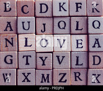 Evidenziato amore parola fatta di legno cubo ruvida lettere. Foto Stock