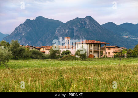 Un piccolo villaggio nel nord Italia prima della tempesta su uno sfondo di alta montagna Foto Stock