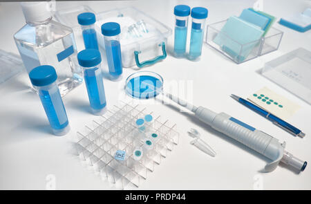 Background scientifico, closeup su campioni in vari tubi di plastica, ice box, penna, note e pipetta automatica Foto Stock
