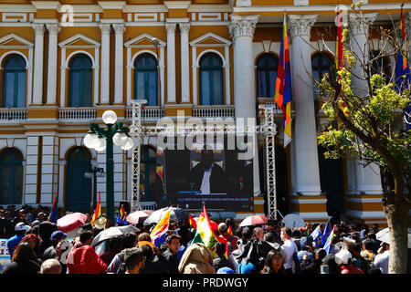 La Paz, Bolivia, 1 ottobre 2018. La gente guarda la sentenza per il caso "obbligo di negoziare l'accesso all'Oceano Pacifico (Bolivia contro Cile)" presso la Corte internazionale di giustizia dell'Aia su uno schermo gigante di fronte all'edificio del Congresso in Plaza Murillo. La Bolivia ha presentato il caso alla CICJ nel 2013; la Bolivia ha perso la sua provincia litoranea verso il Cile durante la guerra del Pacifico (1879-1884) e i negoziati precedenti non hanno compiuto alcun progresso dal punto di vista della Bolivia. Credit: James Brunker/Alamy Live News Foto Stock