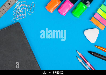 Accessori di cancelleria o scuola merci giacciono su sfondo blu. Vista dall'alto. Foto Stock