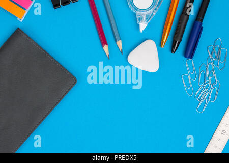 Accessori di cancelleria o scuola merci giacciono su sfondo blu. Vista dall'alto. Foto Stock