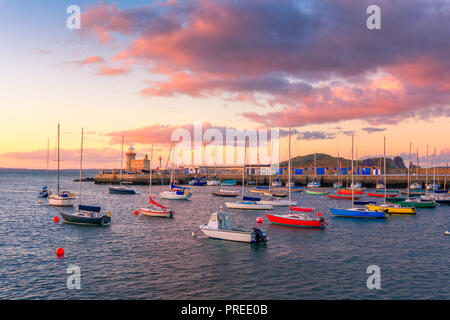 Un tramonto meraviglioso a Howth, Dublino, Irlanda. La vista sulla Howth Faro e barche colorate in primo piano. Foto Stock
