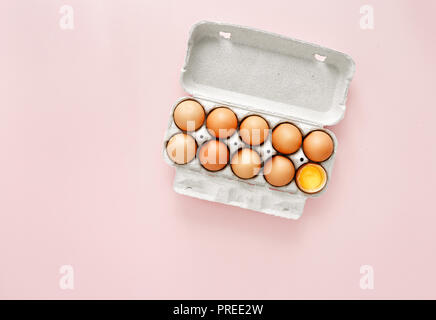 Rosolare le uova in una scatola di cartone su sfondo rosa vista superiore laici piatta Foto Stock