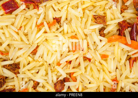 Texture di sfondo di riso basmati con secchi carote, cipolle, paprica, pomodoro, aglio e spezie di massa (curcuma, coriandolo e peperoncino). Top v Foto Stock