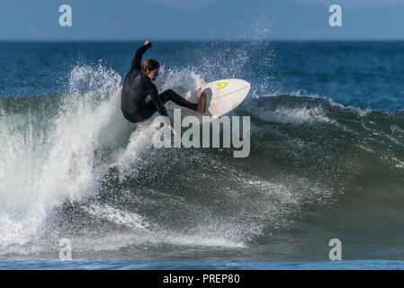 Surfer in nero muta scivola lungo il labbro di beccheggio di una onda a Surfer's Knoll, Ventura, la California il 1 ottobre 2018. Foto Stock