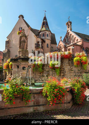 Castello, Chiesa e fontana chiamata San Leon sulla piazza centrale di Eguisheim villaggio in Francia. Eguisheim è un comune in Alsazia. Foto Stock