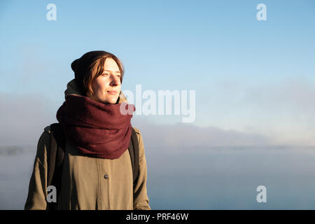 Ritratto di donna in piedi nella luce del sole di mattina. Escursionista femmina godendo Rising Sun in un bellissimo sfondo naturale coperta di nebbia Foto Stock