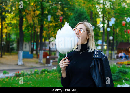 La ragazza di occhiali da sole mangia la caramella di cotone Foto Stock