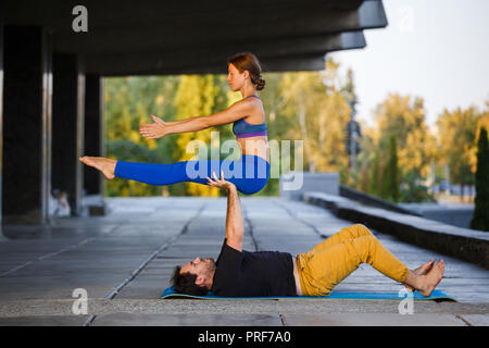 Giovane ragazza e la pratica di acro yoga nella città sulla strada Foto Stock