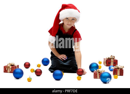 Carino bambina in una Santa Claus cappuccio con baubles di Natale su uno sfondo bianco, isolato Foto Stock