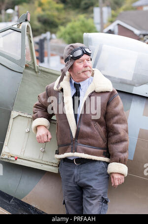 Ri-enactor posa contro una replica di Spitfire e indossando degli anni quaranta piloti di stile vestito a Welshpool 1940s Weekend Foto Stock