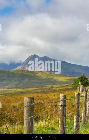 Vista delle nuvole ondenti sopra la vetta distante del Monte Snowdon (Yr Wyddfa in galles del Nord) nel pomeriggio estivo. Foto Stock