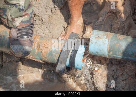 Lavoratori gamba riparazione stomp sulle tubature rotte al foro fix perdita acqua a big sulla strada Foto Stock