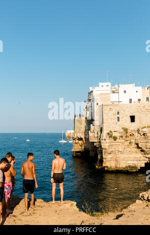 Giovani uomini prepararsi a saltare fuori scogliere in grotta piana a Polignano a Mare, Puglia, Italia Foto Stock