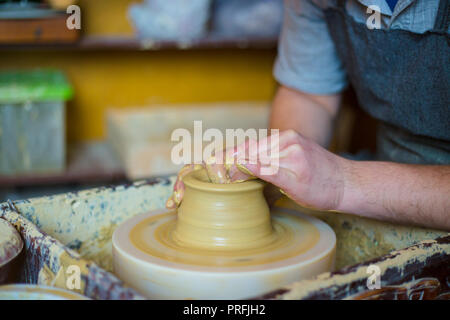 Professional potter maschio lavora con argilla sul tornio del vasaio in officina, studio. Fatti a mano, arte e artigianato concept Foto Stock