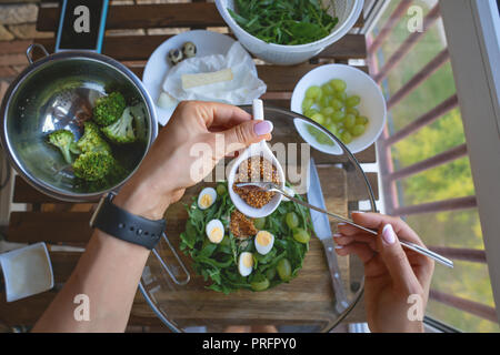 Donna femmina mani di legno sul tavolo di cucina con le verdure di cottura Ingredienti, cucchiaio e strumenti, vista dall'alto, telefono. Spazio libero. Foto Stock