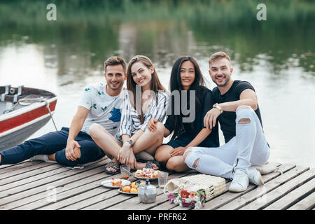 Gruppo di felice giovani amici rilassante sul fiume molo in legno. La vacanza estiva concept Foto Stock