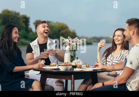 Happy amici divertendosi durante la cena nel ristorante all'aperto. Cibo, divertimento e concetto di pranzo Foto Stock