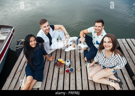 Gruppo di felice giovani amici rilassante sul fiume molo in legno. Vista dall'alto. La vacanza estiva concept Foto Stock