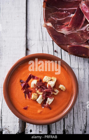 Elevato angolo di visione di un vaso di terracotta con lo spagnolo salmorejo cordobes o porra antequerana, un freddo minestra di pomodoro, guarnita con prosciutto Serrano e crostini, Foto Stock