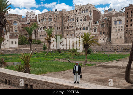 Un uomo in abiti tradizionali si erge di fronte di edifici a più piani in pietra il 4 maggio 2007 a Sanaa, Yemen. Foto Stock