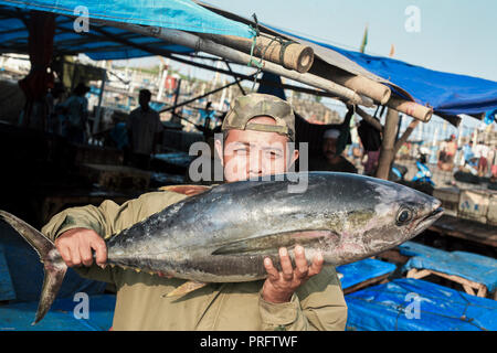 L'uomo mantiene fresco il tonno pescato il pesce al mercato umido nel West Java, Indonesia Foto Stock