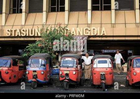 I risciò auto Bajaj aspettano i passeggeri fuori dalla stazione ferroviaria di Gondangdia a Giacarta, Indonesia Foto Stock