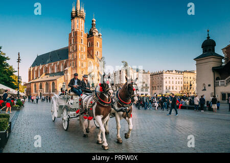 Cracovia in Polonia - Agosto 27, 2018: due cavalli in un vecchio stile pullman in Piazza della Città Vecchia In Nuvoloso Giorno d'estate. Santa Maria la Basilica di famoso segno distintivo su BA Foto Stock