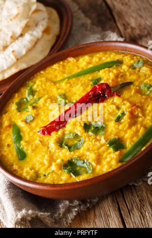 Zuppa di lenticchie Dal Tadka in un vaso di ceramica con pane naan su uno sfondo di legno. Close up. In verticale Foto Stock