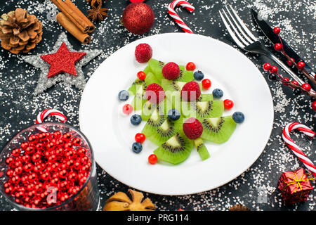 Kiwi albero di natale con lampone, mirtillo e cowberry sul tavolo con decorazione Foto Stock