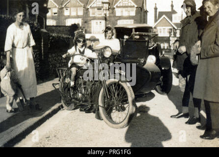 Ragazzo che indossa il casco in pelle e occhiali seduto su un 1918 Harley Davidson combinazione per la strada circa 1918 Foto Stock