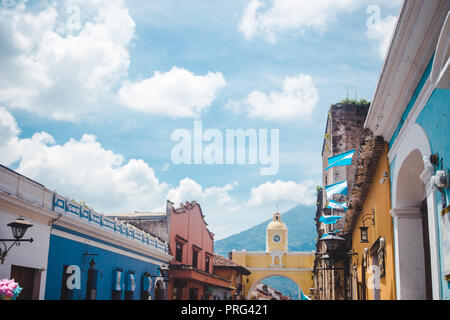 Bandiere guatemalteco fly che conduce fino al famoso arco giallo di Santa Catalina in Antigua Guatemala su un soleggiato giorno di indipendenza Foto Stock