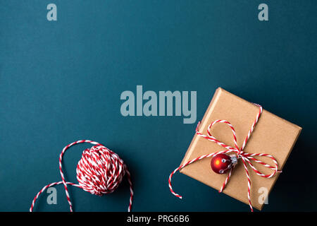 Confezione regalo avvolti in carta kraft e legato con candy cane Natale fune su sfondo blu scuro. Concetto di vacanza, vista dall'alto. Foto Stock