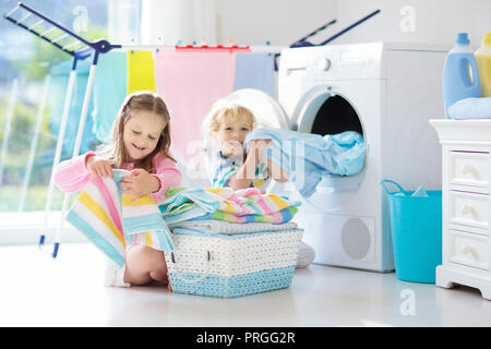 Bambini nella stanza lavanderia con lavatrice o asciugatrice. I bambini  aiuto con faccende familiari. Moderni dispositivi domestici e di detersivo  di lavaggio in bianco s Foto stock - Alamy