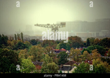 Glasgow, Scotland, Regno Unito, 3 ottobre, 2018. Regno Unito Meteo. Dark nuvole temporalesche e visibilità limitata come la nebbia nasconde il lontano orizzonte oltre l'Est Ovest skyline del sud di Glasgow guardando a sud come frondoso sobborgo di knightswood e le ultime vestigia di Clyde cantieristica la Clyde titan, spicca contro la sbiadita Queen Elizabeth Hospital di Govan del suo campo da golf mostrano i primi segni di autunno . Gerard Ferry/Alamy news Credito: gerard ferry/Alamy Live News Foto Stock