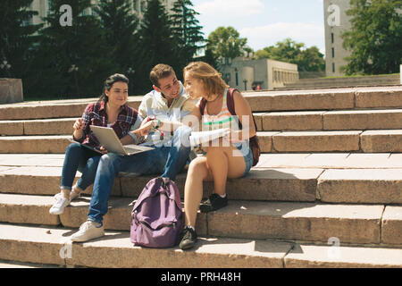 Un gruppo di tre studenti seduti sulle scale Foto Stock