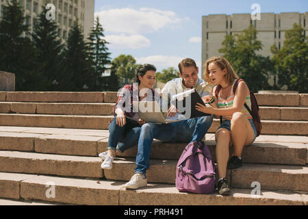 Un gruppo di tre studenti seduti sulle scale Foto Stock