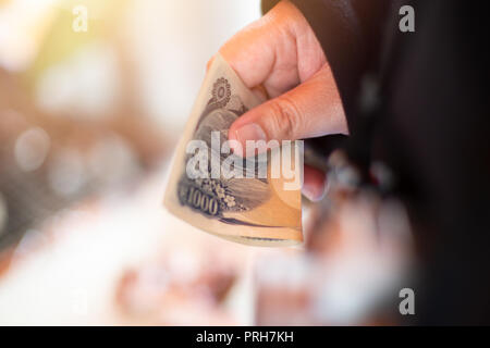 Mano che tiene il Giappone Yen denaro in contanti per pagare per lo shopping. Foto Stock