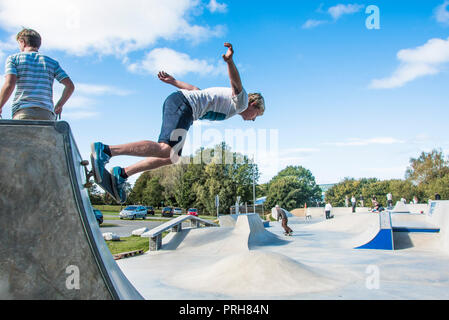 Un guidatore di skateboard di eseguire un trick skateboard su un quarto di tubo in calcestruzzo onde in Newquay in Cornovaglia. Foto Stock