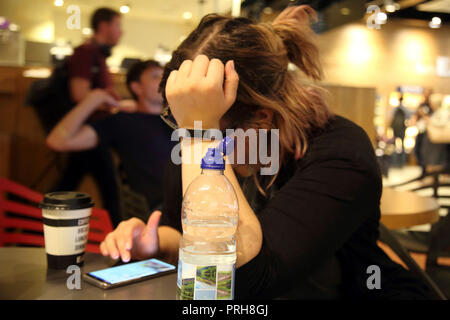 Inghilterra aeroporto di Heathrow Terminal Due donna utilizzando il telefono cellulare Foto Stock