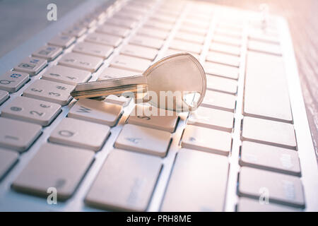 Chiave di metallo su una tastiera bianca - un accesso protetto al computer Concept Foto Stock