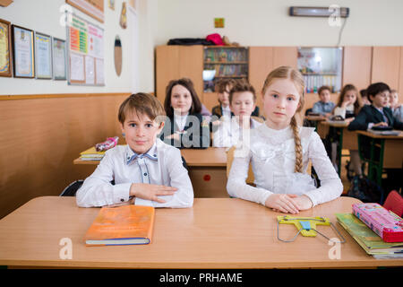 L'Ucraina. Kiev. Il 5 maggio 2018. Scuola Junior, college. Coppia due bambini di nazionalità caucasica, gli alunni di scuola, sit desk classe scuola camera. Sulla tabella libri Foto Stock