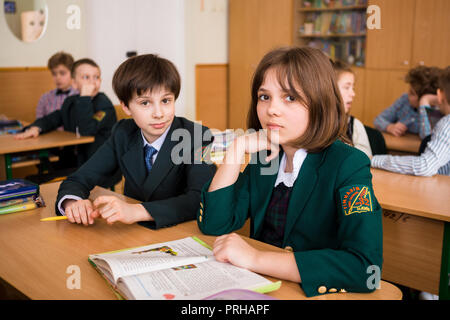 L'Ucraina. Kiev. Il 5 maggio 2018. Scuola Junior, college. Coppia due bambini di nazionalità caucasica, gli alunni di scuola, sit desk classe scuola camera. Sulla tabella libri Foto Stock