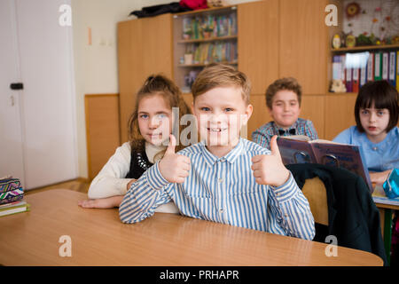L'Ucraina. Kiev. Il 5 maggio 2018. Scuola Junior, college. Coppia due bambini di nazionalità caucasica, gli alunni di scuola, sit desk classe scuola camera. Sulla tabella libri Foto Stock